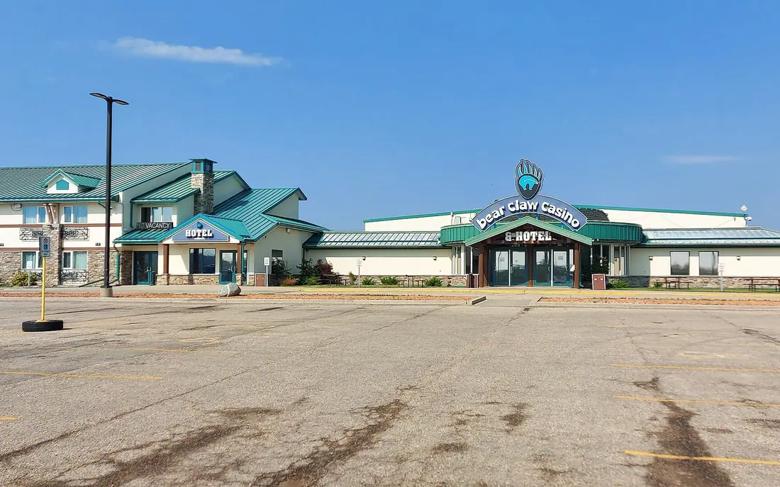 Le Bear Claw Casino et son aile hôtelière aux toits verts, à White Bear First Nations, vus de l'autre côté du stationnement vide