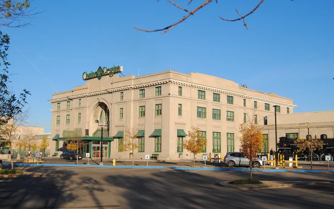 Casino Regina in the former Union Station, a pale stone building with an arched entrance, green awnings and the Casino Regina sign on the roof, on a sunny autumn day